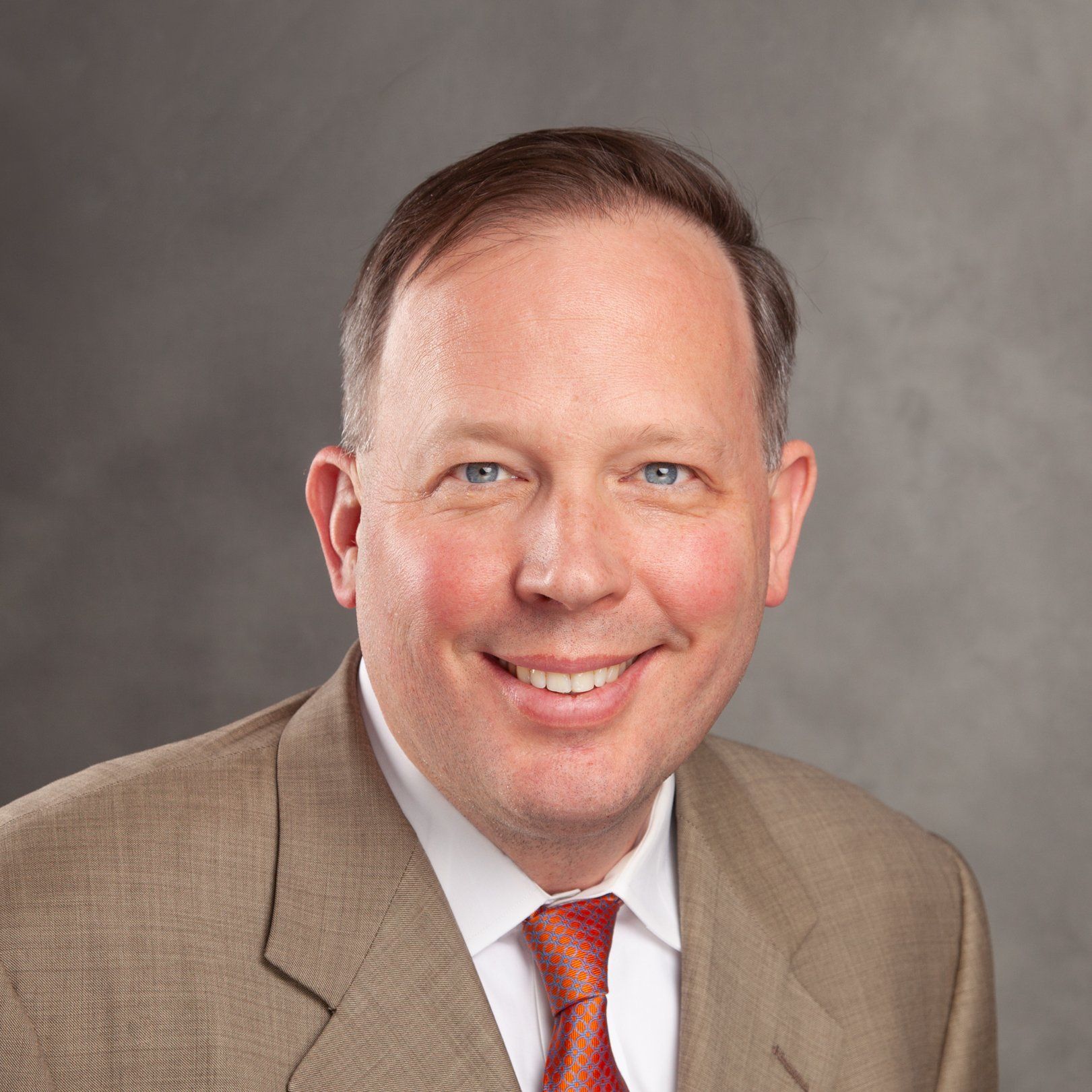 A man in a suit and tie is smiling for the camera.