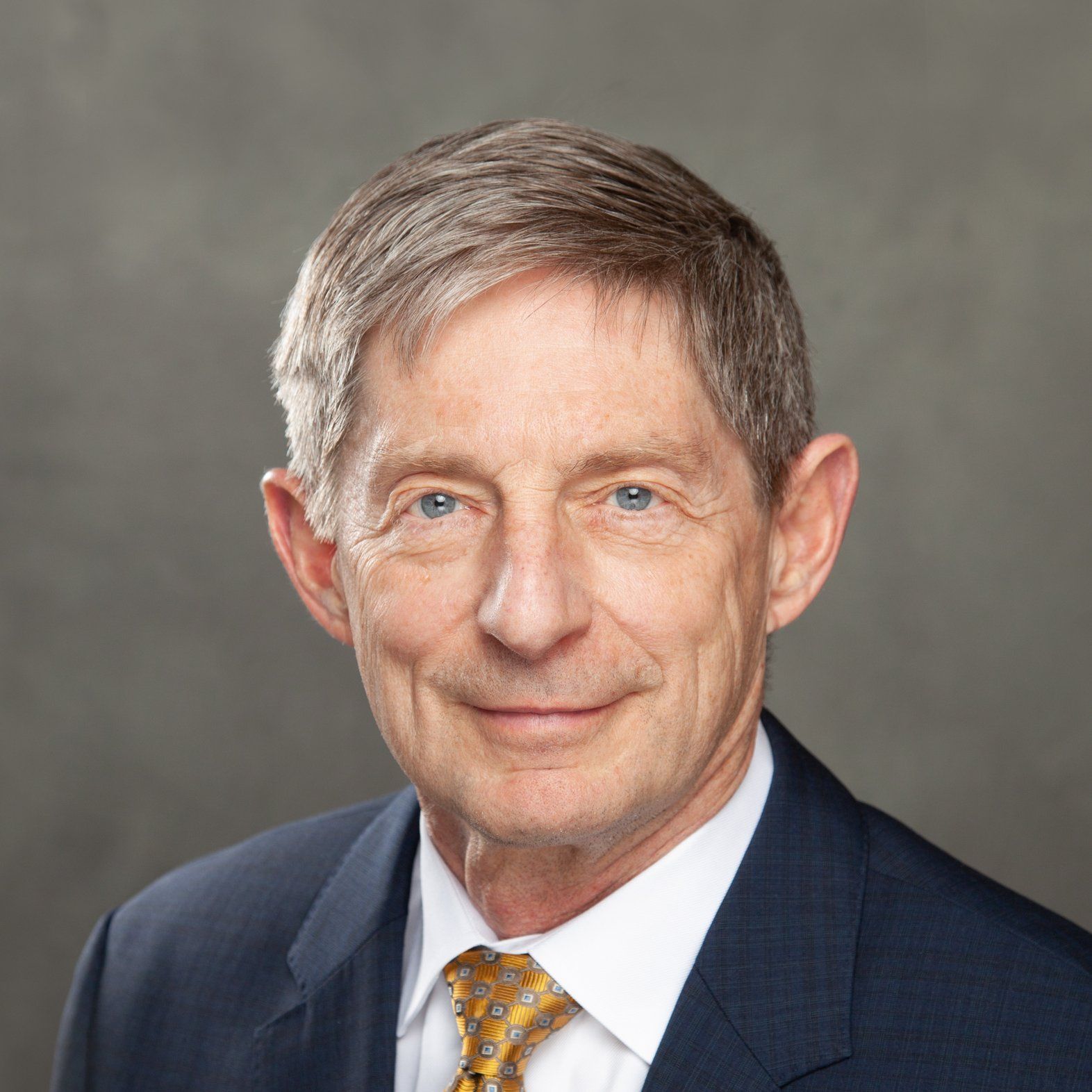 A man in a suit and tie is smiling for the camera