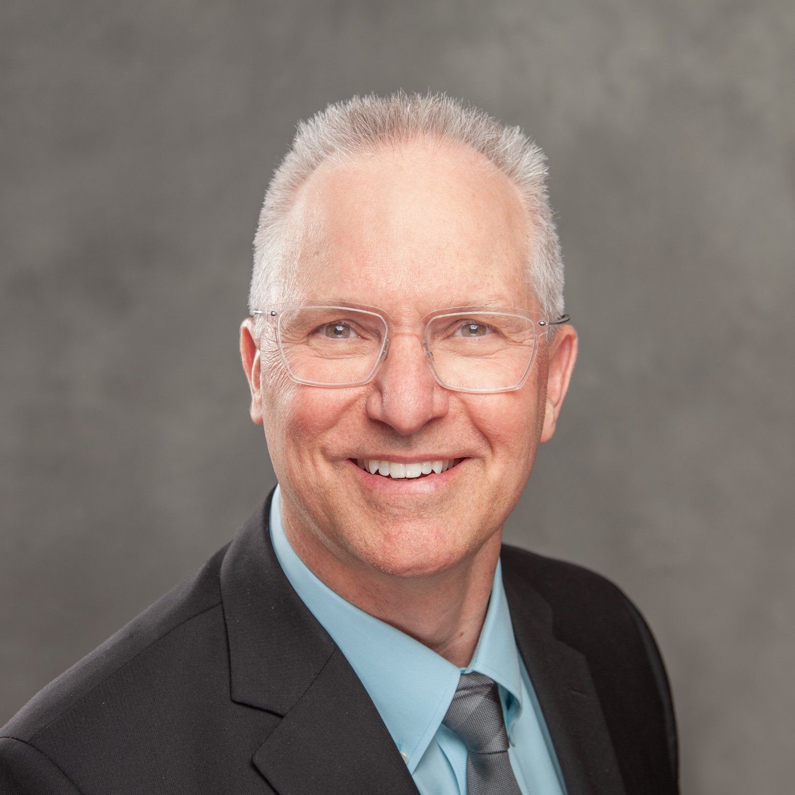 A man in a suit and tie is smiling for the camera.