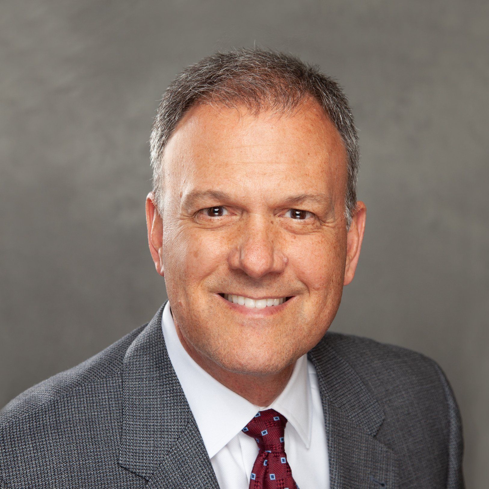A man in a suit and tie is smiling for the camera