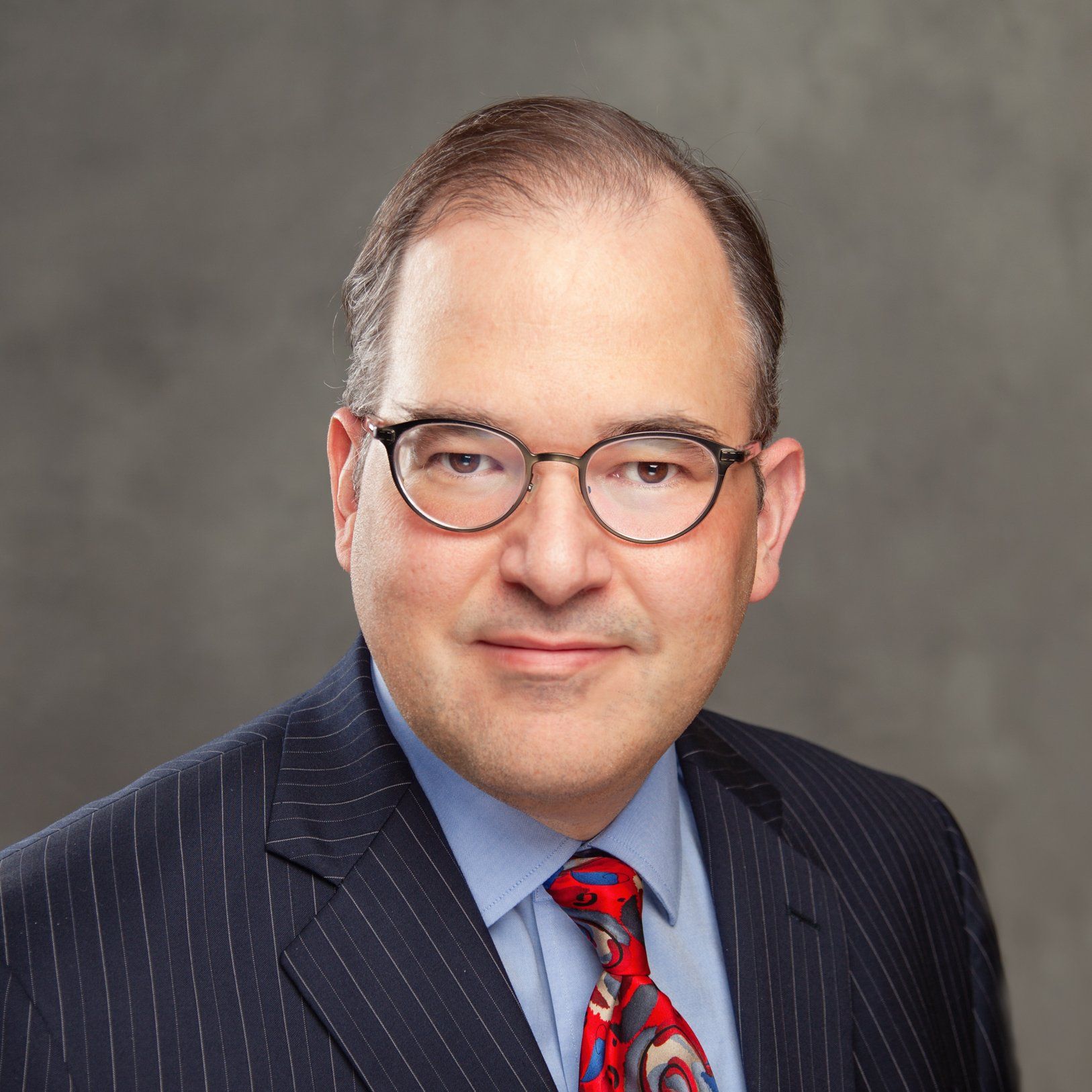 A man in a suit and tie is wearing glasses.