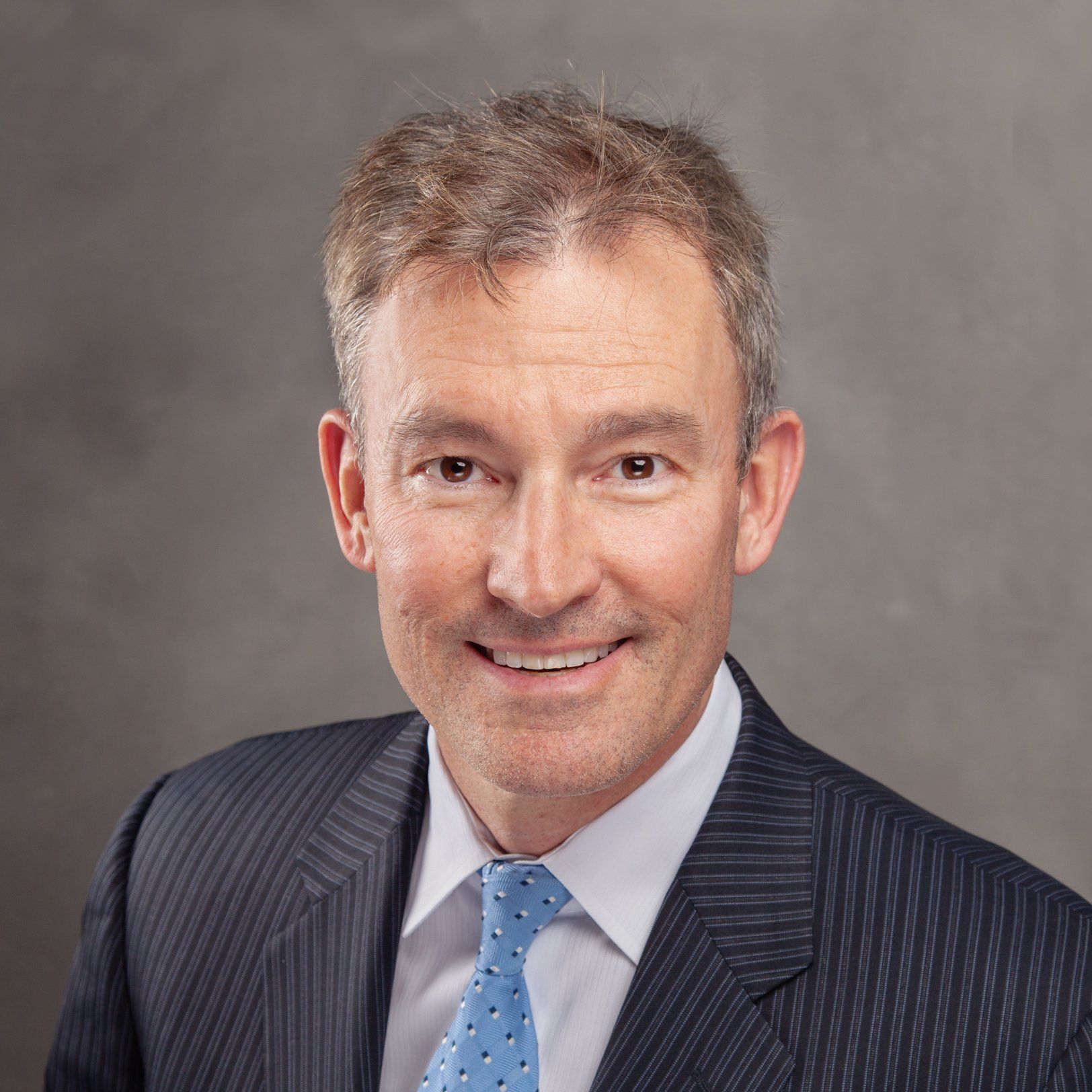 A man in a suit and tie is smiling for the camera.