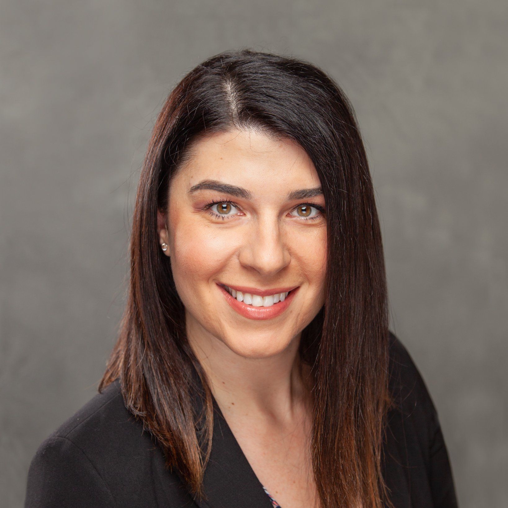 A woman in a black jacket is smiling for the camera.