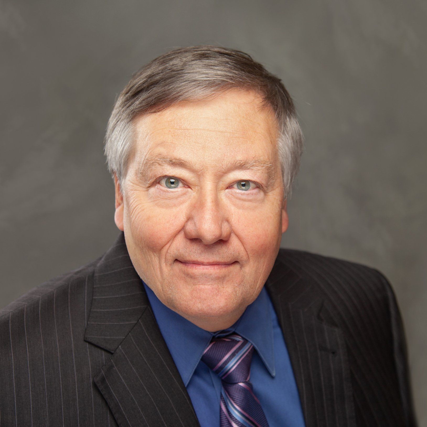 A man in a suit and tie is smiling for the camera