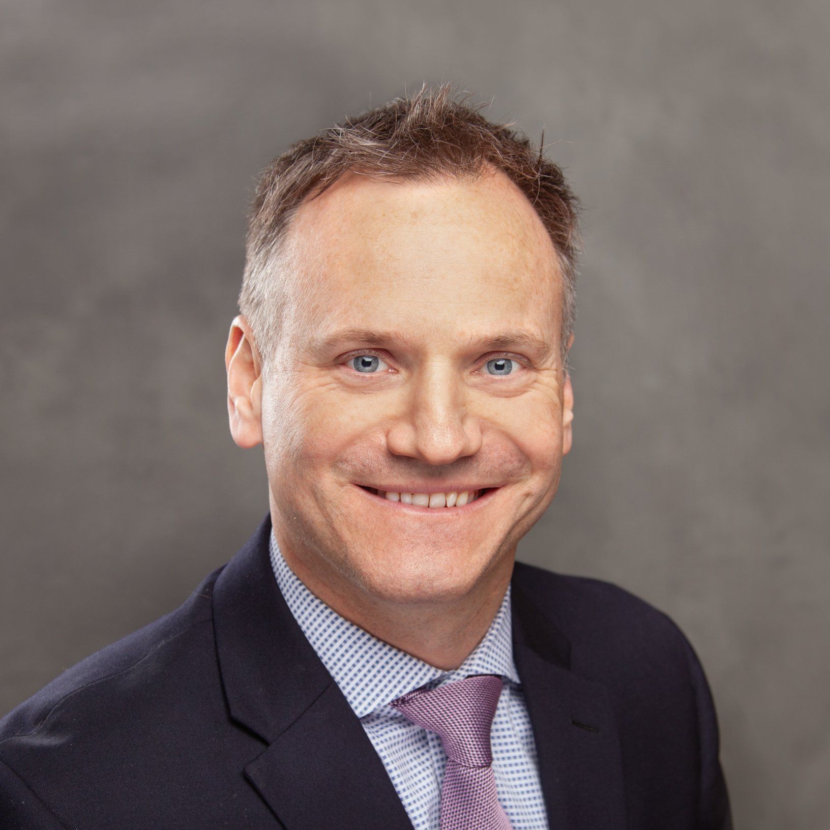 A man in a suit and tie is smiling for the camera.