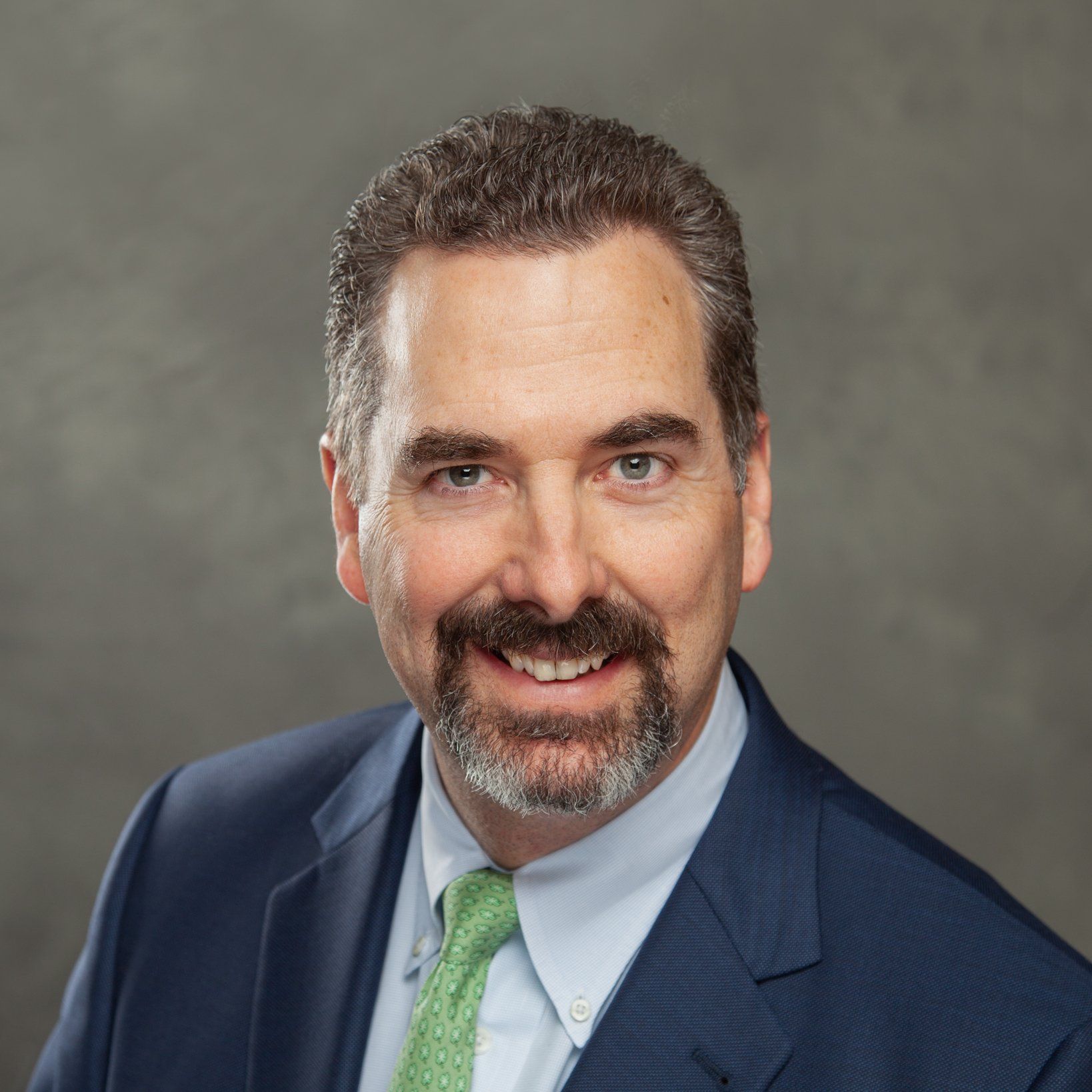 A man in a suit and tie is smiling for the camera.