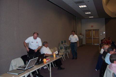 A group of men are sitting at a table with laptops