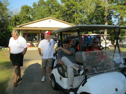 A group of people are standing around a golf cart.