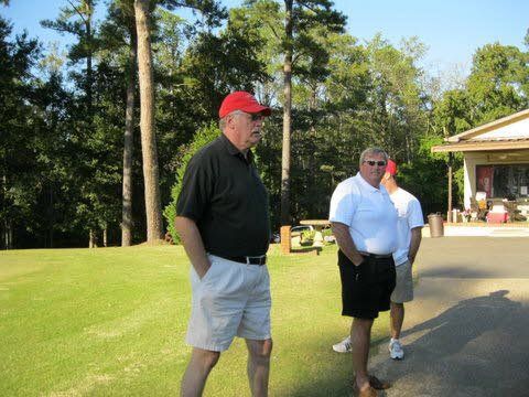 Two men standing on a golf course talking to each other