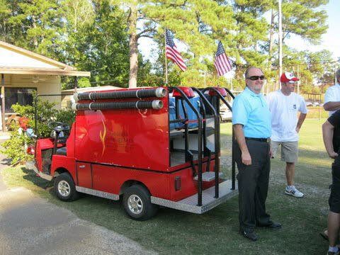 A group of men standing in front of a red golf cart