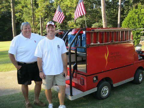 Two men are standing in front of a red golf cart