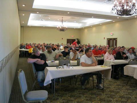 A large group of people are sitting at tables in a conference room.
