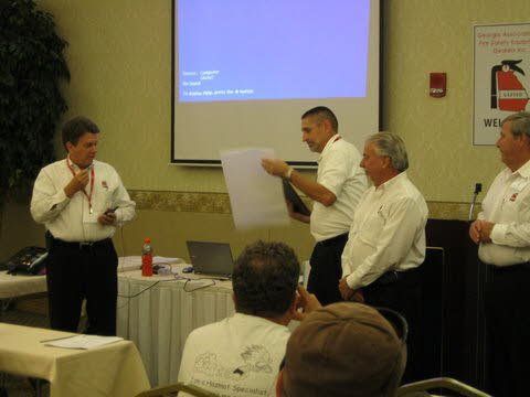 A group of men standing in front of a projector screen