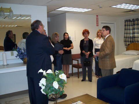 A group of people are standing in a room talking to each other.