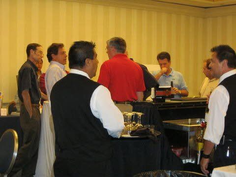 A group of men are standing in a room talking to each other