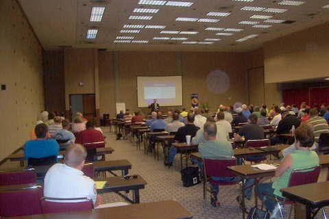 A large group of people are sitting at tables in a conference room.