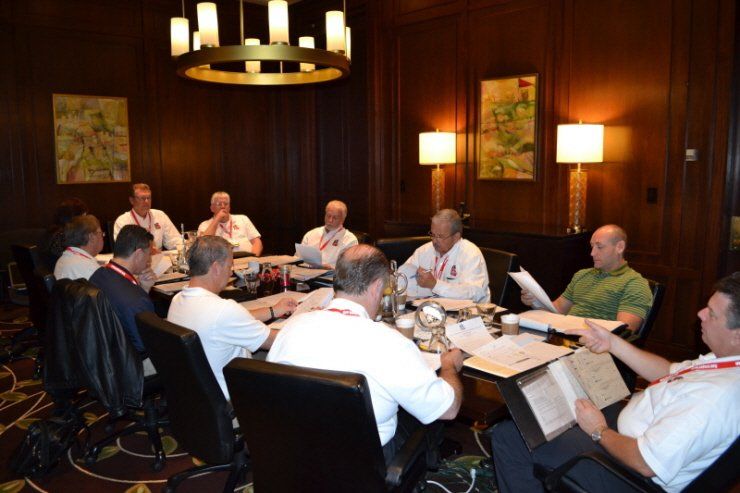 A group of men are sitting around a table in a conference room
