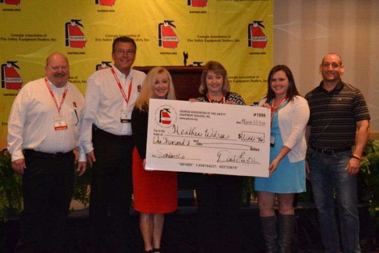 A group of people holding a large check that says