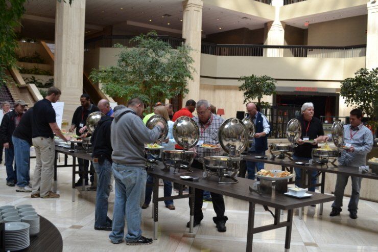 A group of people are standing around buffet tables.