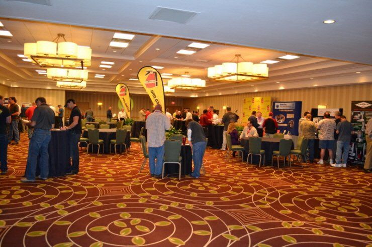 A group of people are gathered in a large room with tables and chairs