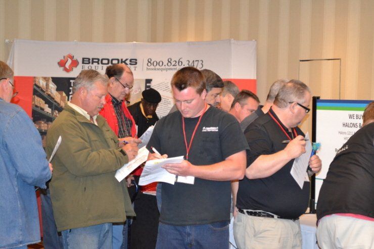 A group of men are standing in front of a brooks sign