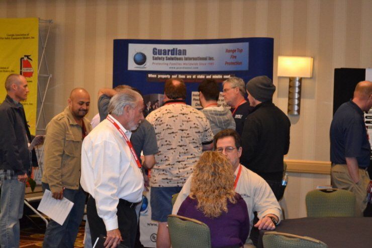 A group of people are standing around a table in front of a sign that says guardian