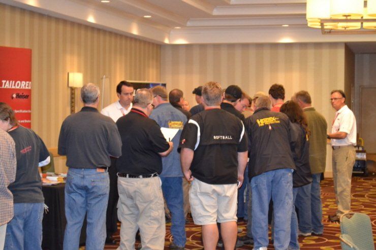 A group of men are standing in a room with a sign that says tailorall