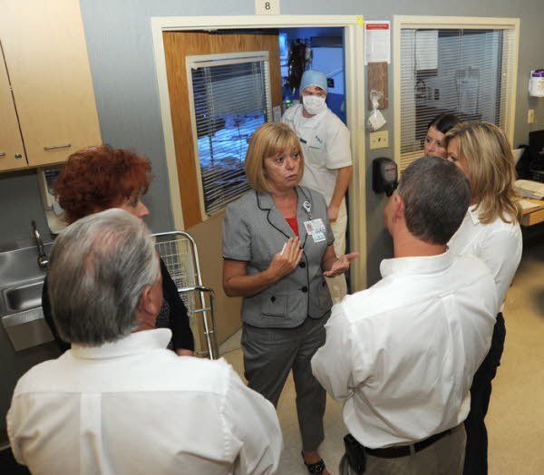 A group of people standing around a woman in a suit