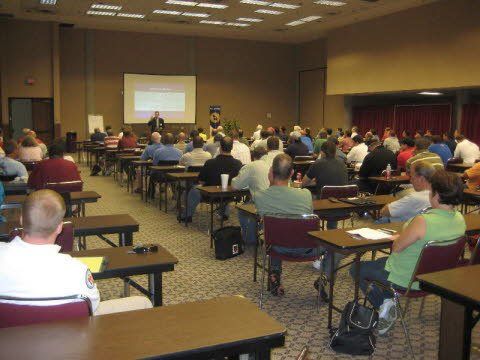 A large group of people are sitting at tables in a conference room