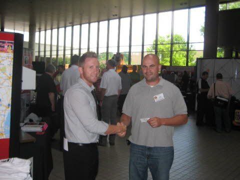 Two men shaking hands in a room with a lot of windows