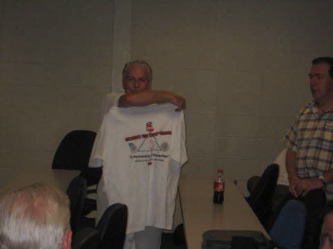 A man is holding a t-shirt in front of a group of people.
