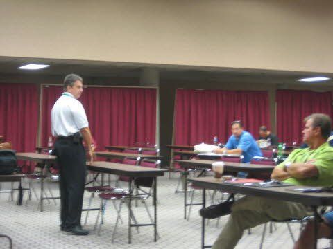 A man standing in a room with people sitting at tables