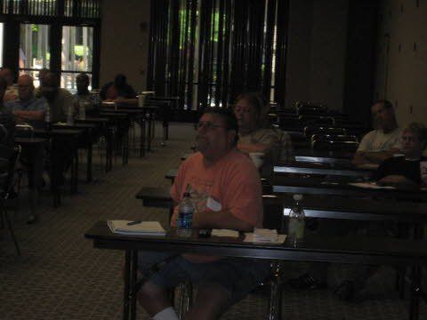 A man sits at a table with a bottle of water in his hand