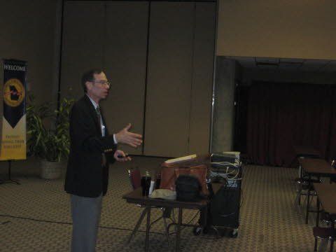 A man in a suit and tie is giving a presentation