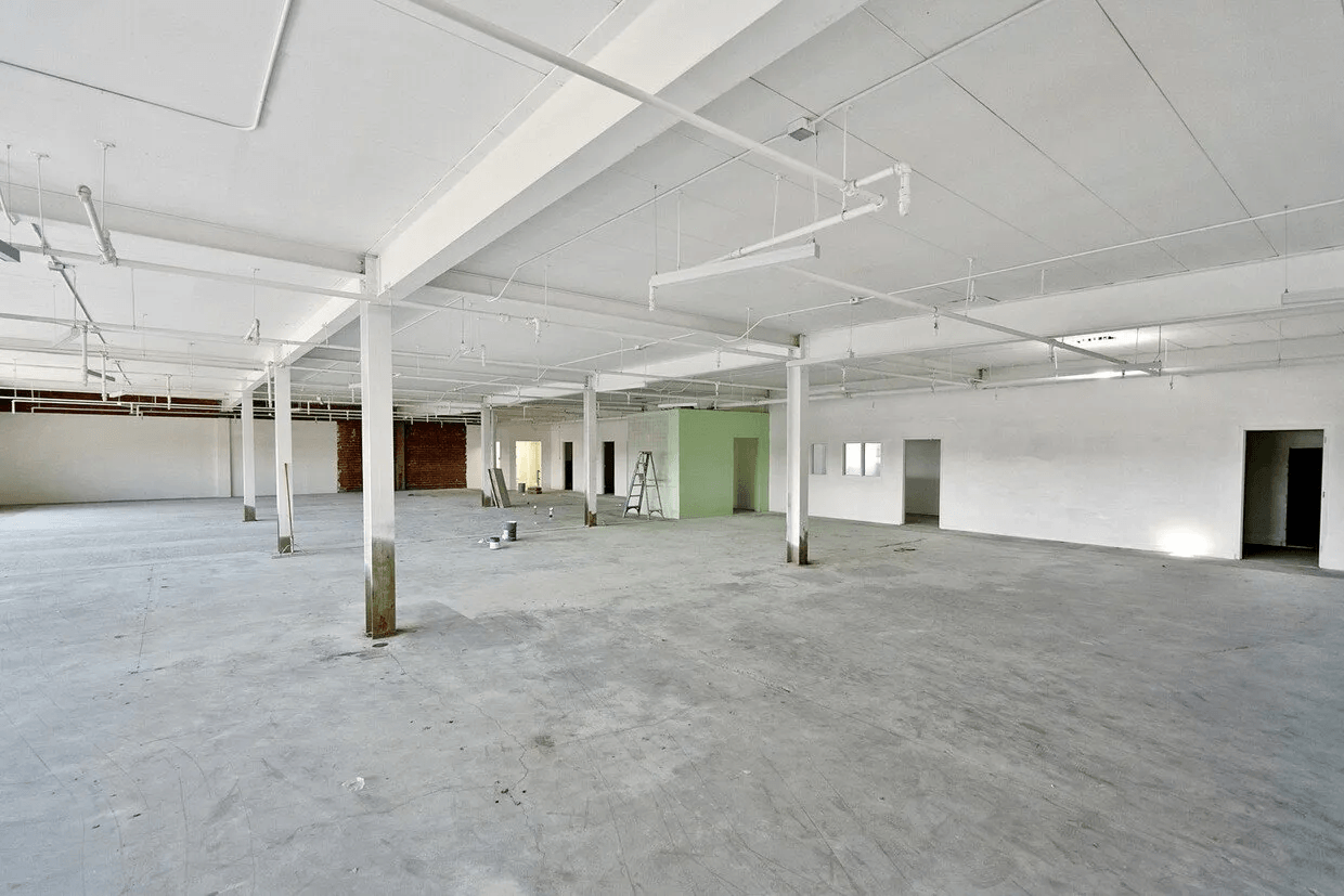 A large empty building with concrete floors and white walls.