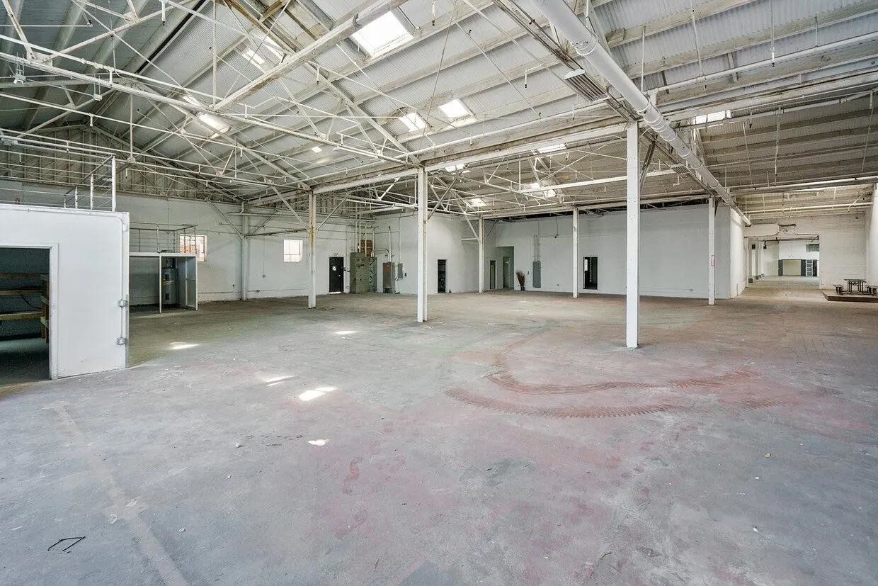 A large empty warehouse with a lot of windows and columns.