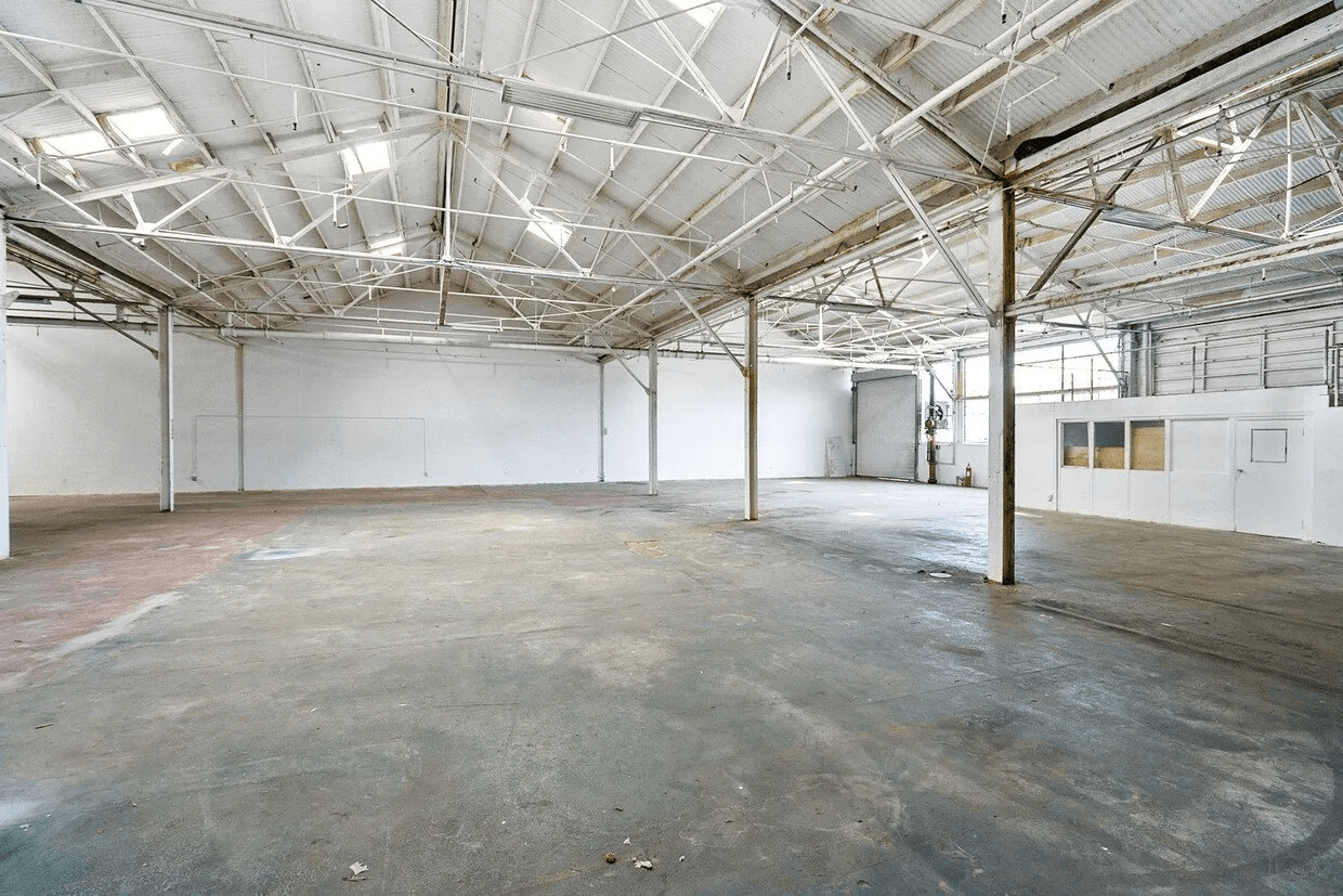 A large empty warehouse with white walls and a metal roof.