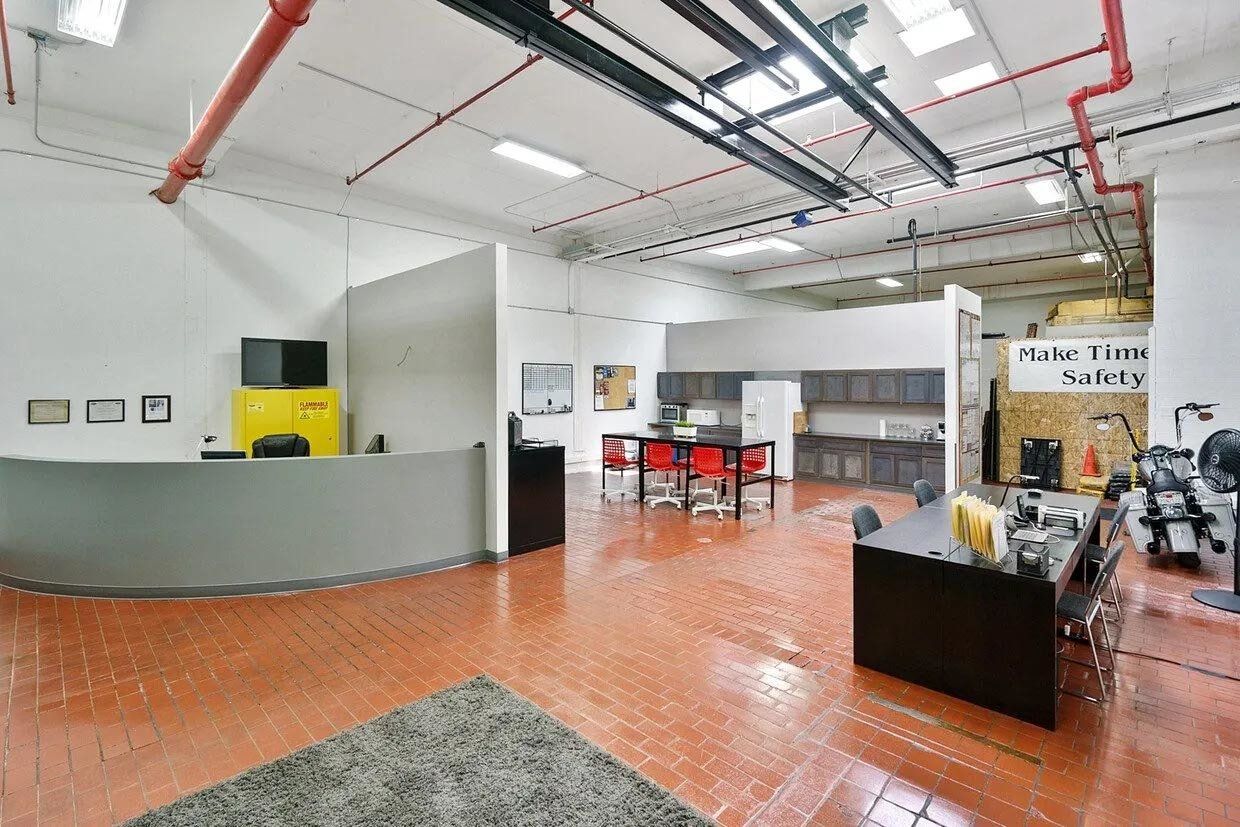 A large room with a reception desk , tables , chairs and a rug.