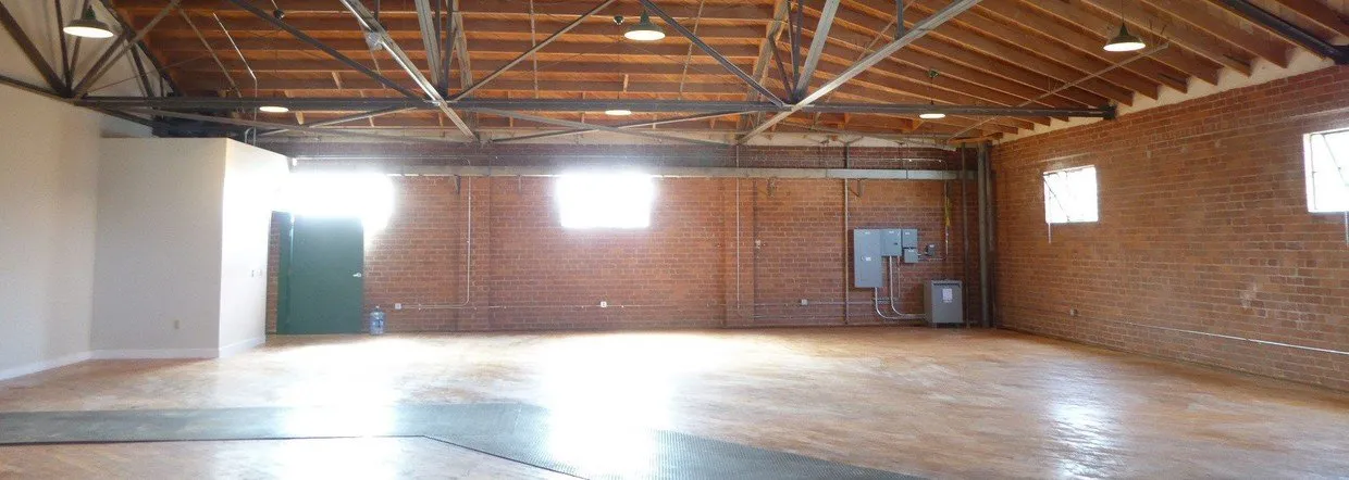 A large empty room with a wooden ceiling and brick walls.