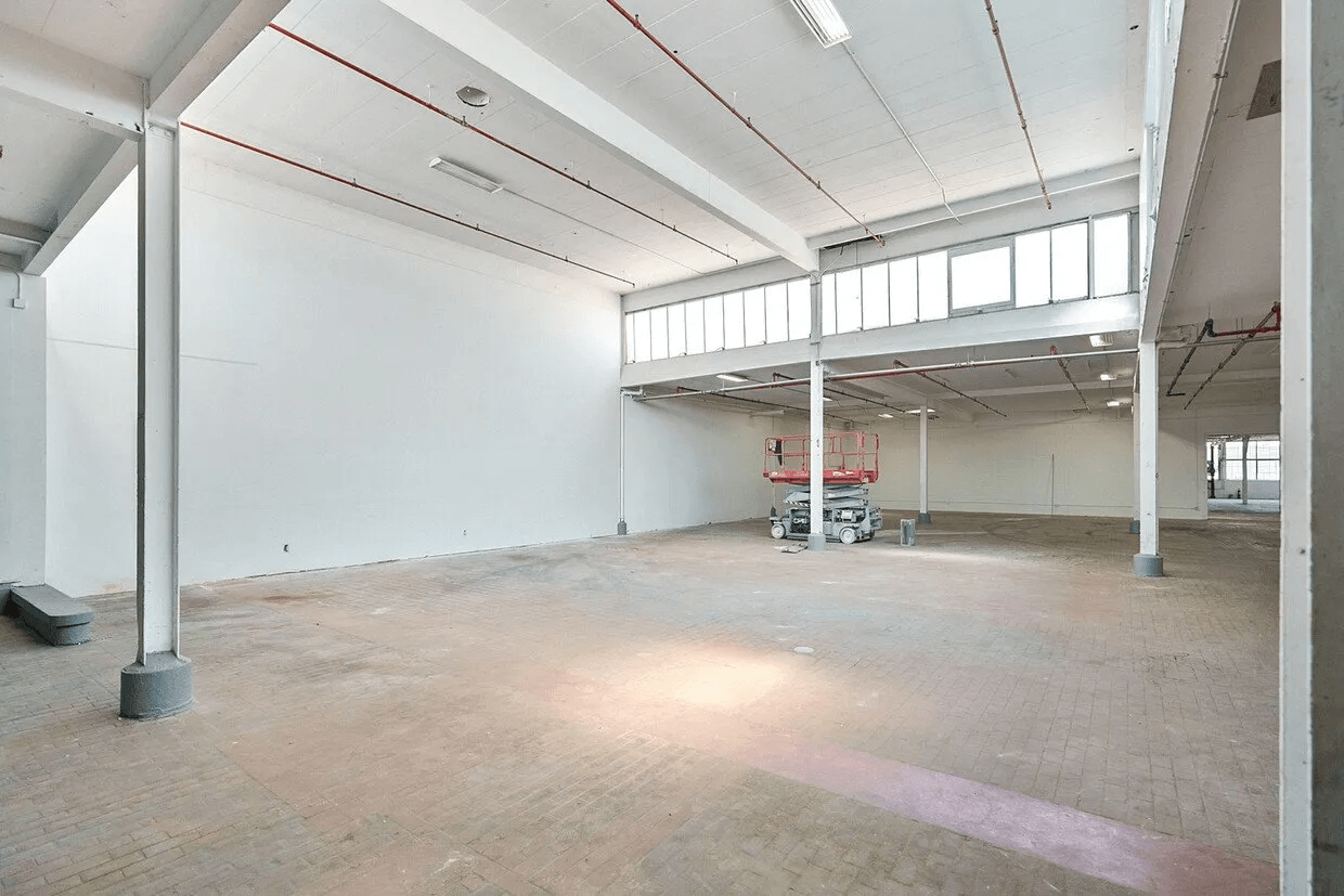 A large empty warehouse with a lot of windows and columns.