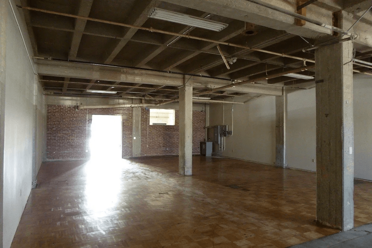 A large empty room with a wooden floor and white walls