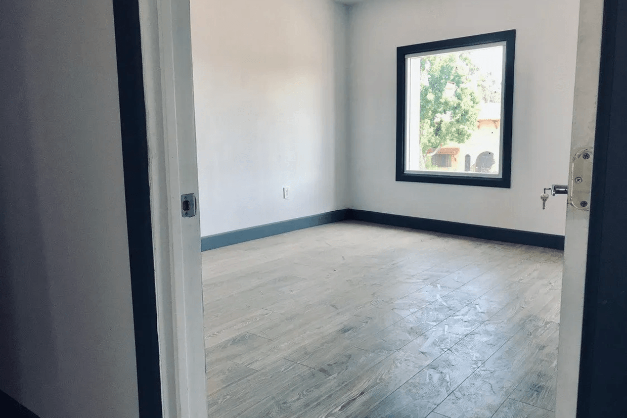 An empty room with hardwood floors and a window.