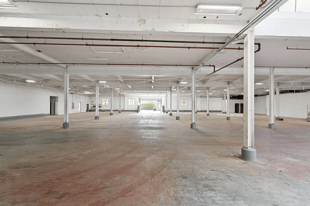 A large empty warehouse with white walls and columns.