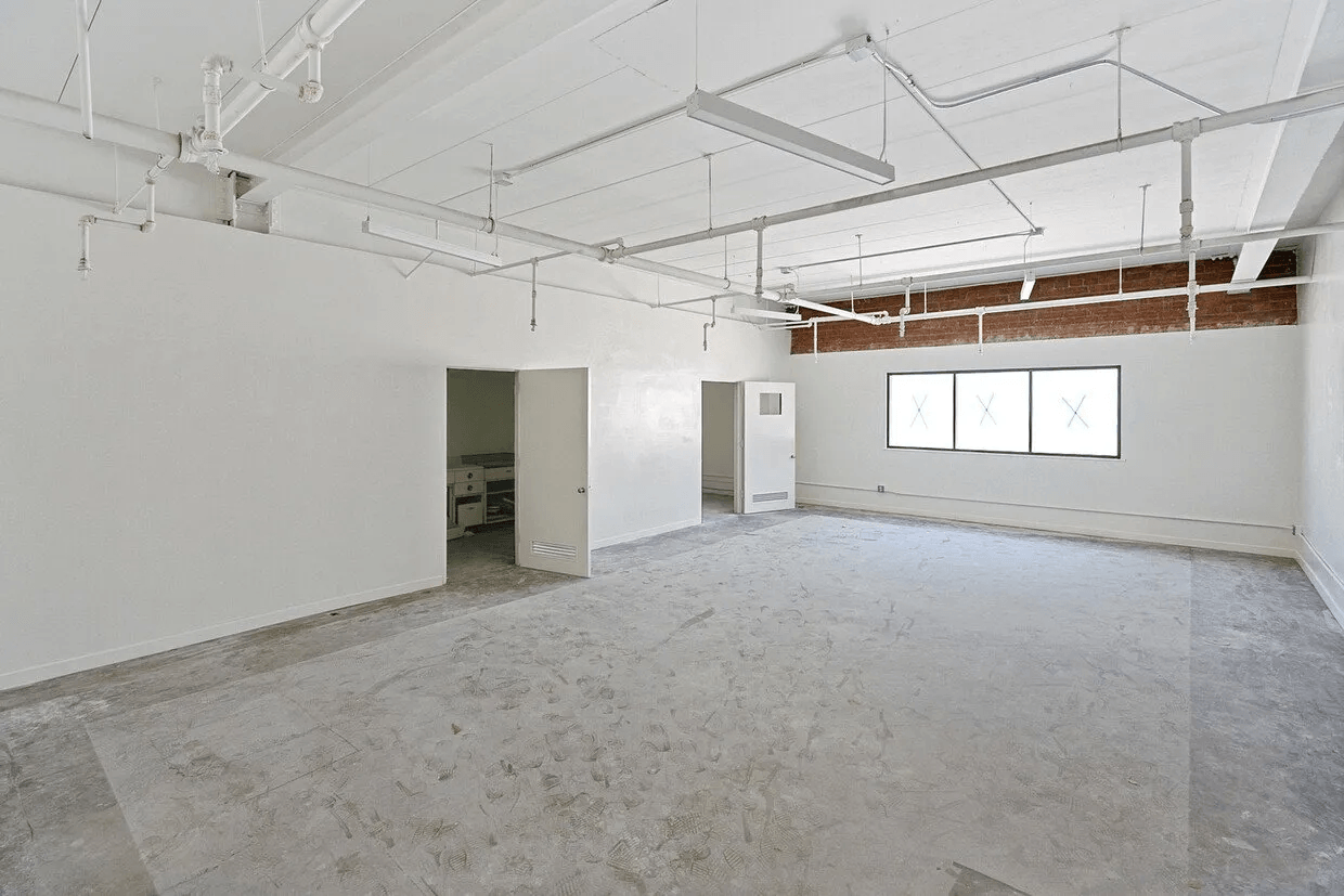 A large empty room with white walls and a concrete floor.