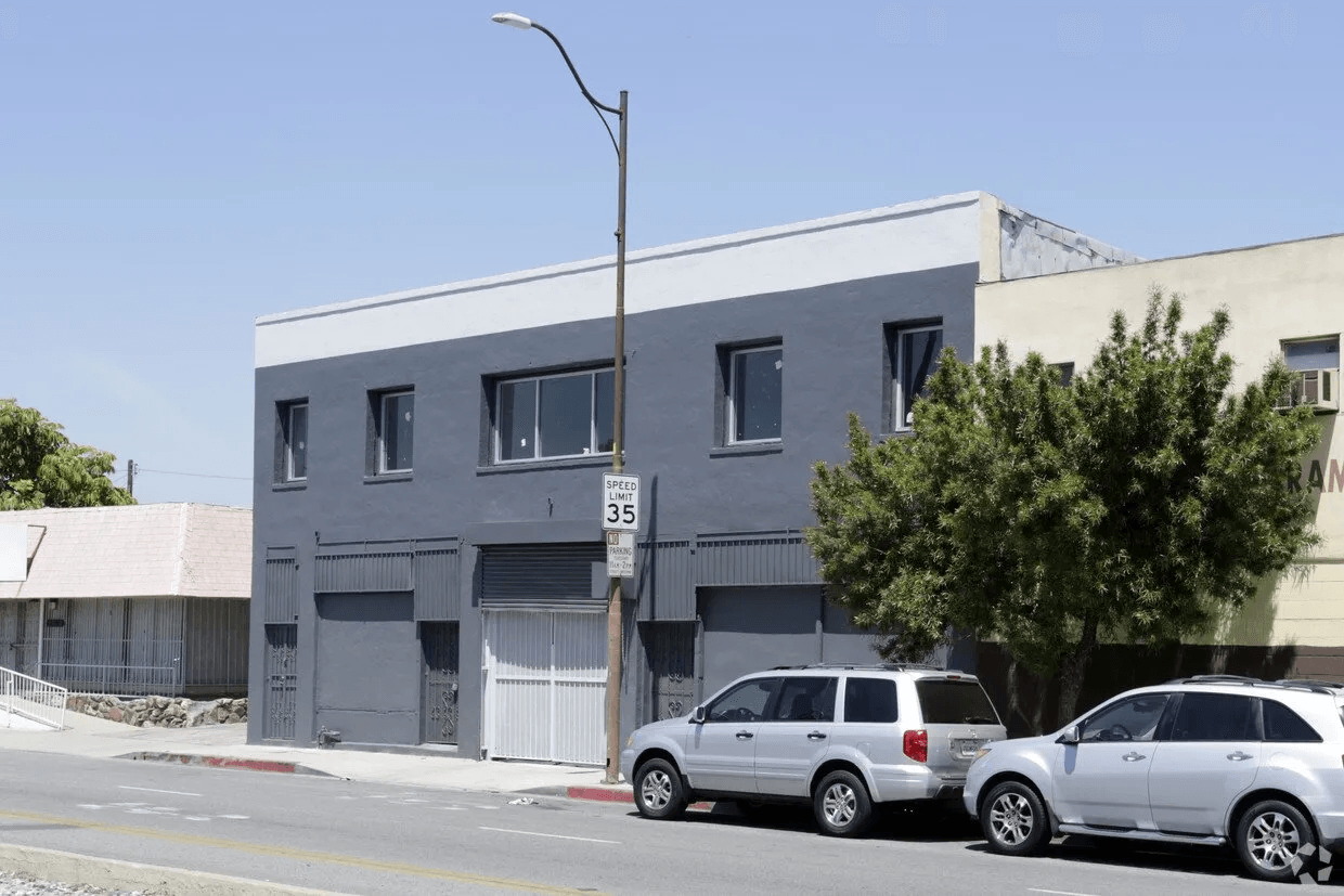 A row of cars are parked in front of a building
