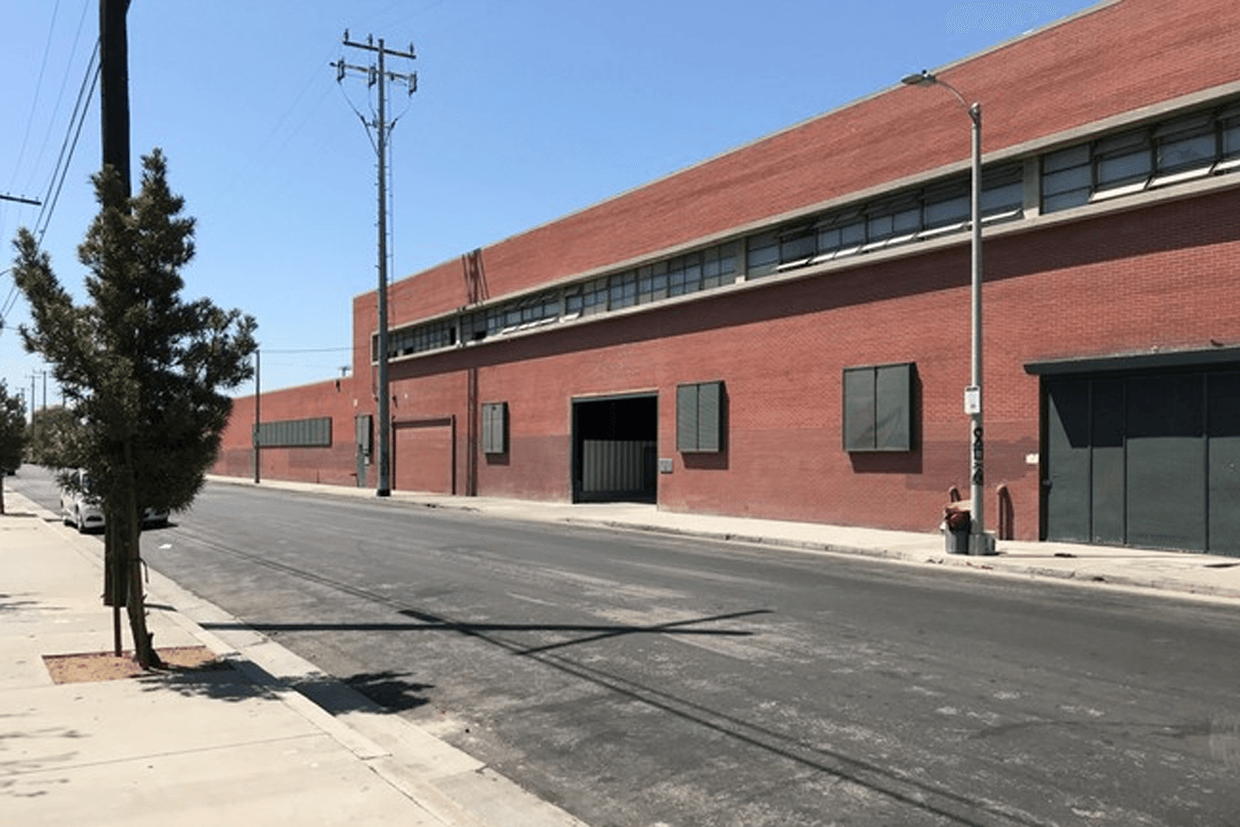 A large red brick building is sitting on the side of a street.
