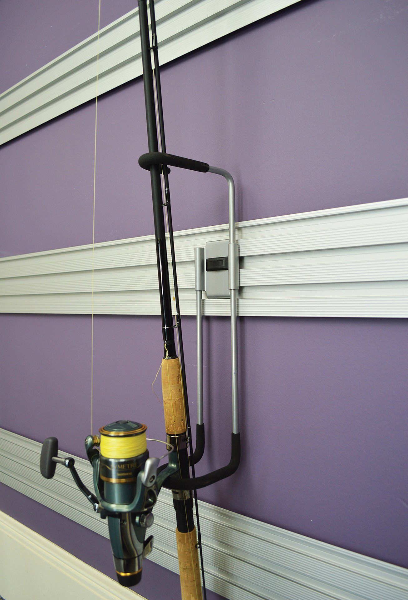 A fishing rod and reel are hanging on a purple wall