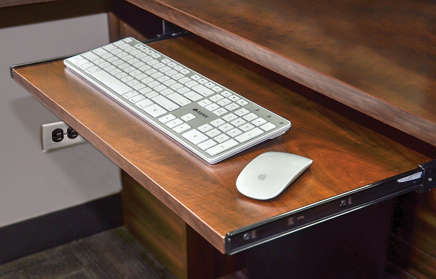 A keyboard and mouse are on a wooden keyboard tray.