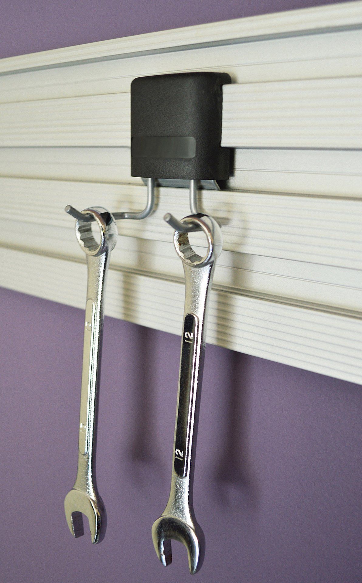 Two wrenches are hanging on a rack on a purple wall.