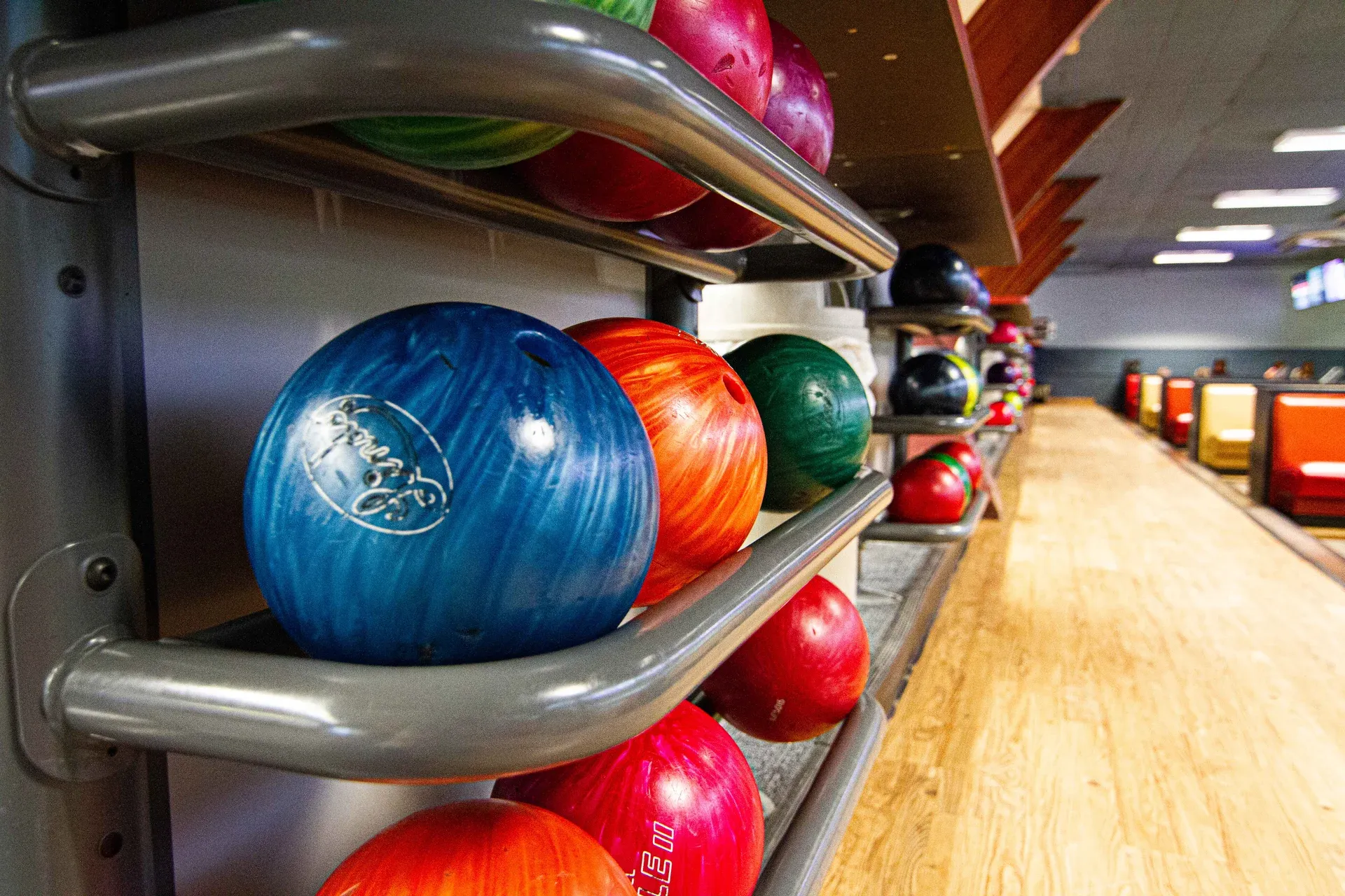 Bowling balls on shelves in a bowling alley, various colors: blue, red, green.